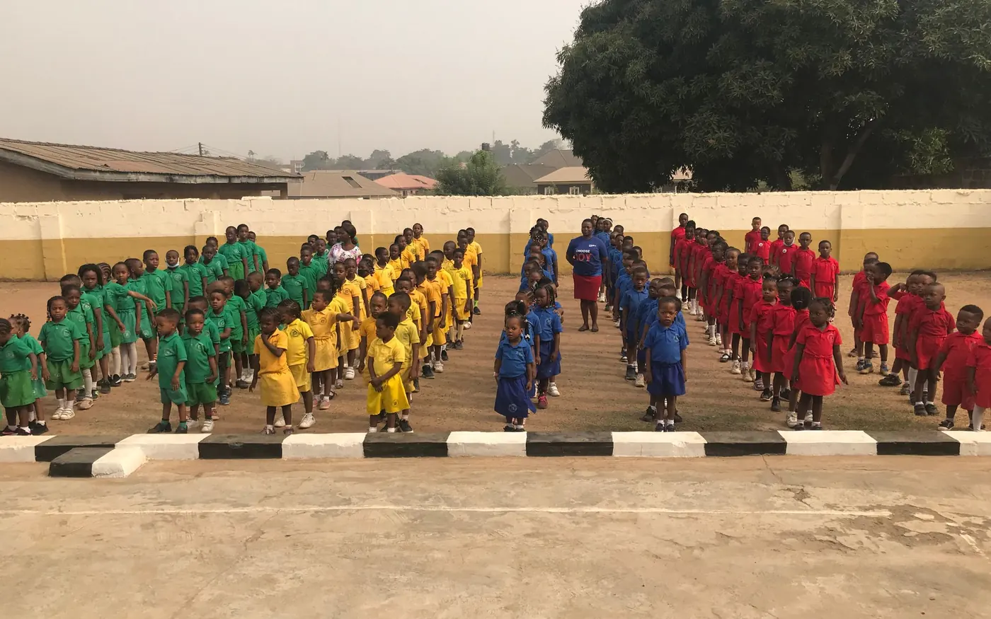 Students lined up in rows across the school ground for morning assembly